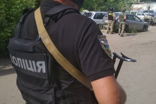 Ukrainian law enforcement officers are seen near a site where a man armed with a grenade holds a policeman hostage in Poltava, Ukraine