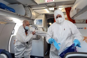 Israeli flight attendants wearing protective gear work in a flight to Israel.