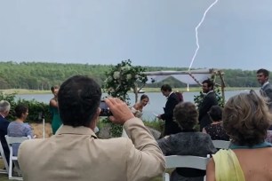 Lightning strikes behind Aaron and Denise Sawitsky as they are married Saturday, Aug. 22, 2020.