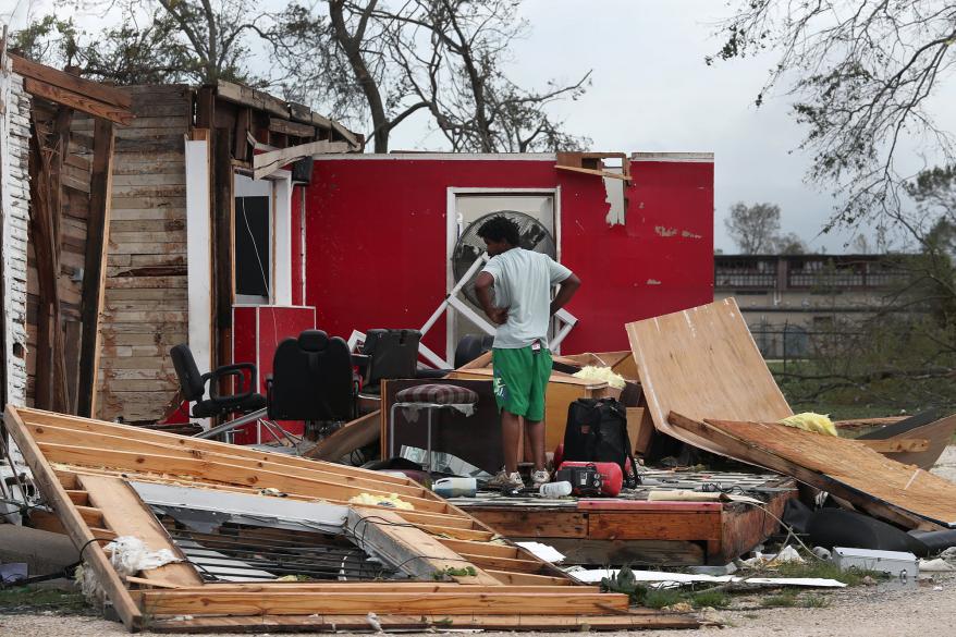 A man surveys what is left of his uncles barber shop after Hurricane Laura.