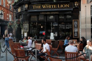 People sit outside the White Lion pub in London