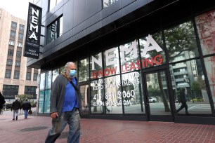 A pedestrian walks by a building advertising apartment leases in San Francisco, California