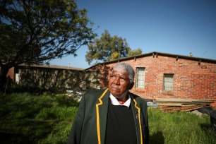 Former rugby player Broadhurst Cona walks through the garden of the only two remaining houses in the community from which he was removed under apartheid, in Simon's Town, near Cape Town, South Africa.