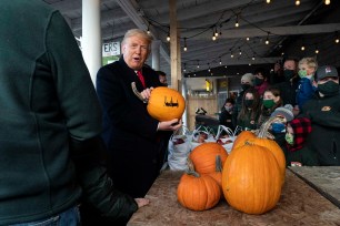 President Donald Trump holds an autographed pumpkin during a visit to the Treworgy Family Orchards