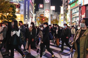 Pedestrians wearing protective masks walk a Shibuya crossway in Tokyo