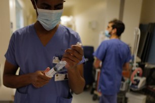 Nurse Hyad Boina, left, prepares a syringe to use in the treatment of a patient in room No. 9 in his battle against COVID-19 at Bichat Hospital, AP-HP, in Paris Tuesday, Dec. 1, 2020.