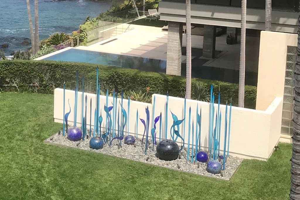 A dispute over an outdoor glass sculpture, above, at a Laguna Beach home owned by Bill Gross and his partner has escalated with neighbor Mark Towfiq and his wife, with both sides calling police and filing legal actions.
