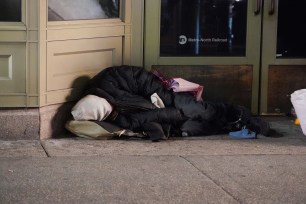 A homeless person sleeping on the sidewalk in NYC.