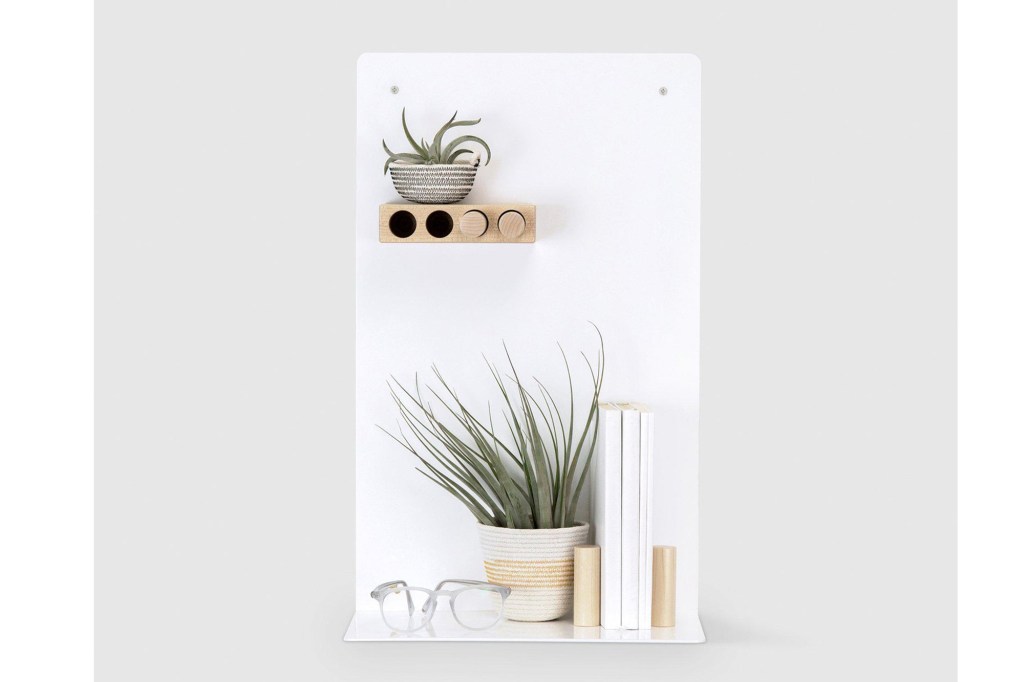 A white shelf with pegs and a plant, glasses and other things on it 