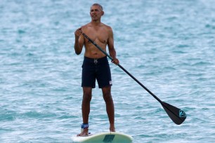 Former President Barack Obama shows off his fit physique during a paddle board session while on vacation in Hawaii.