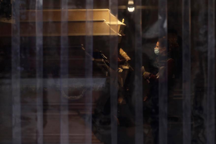 A worker checks a casket inside an overflow cold storage container placed outside a crematorium in Ostrava, Czech Republic, Thursday, Jan. 7, 2021.