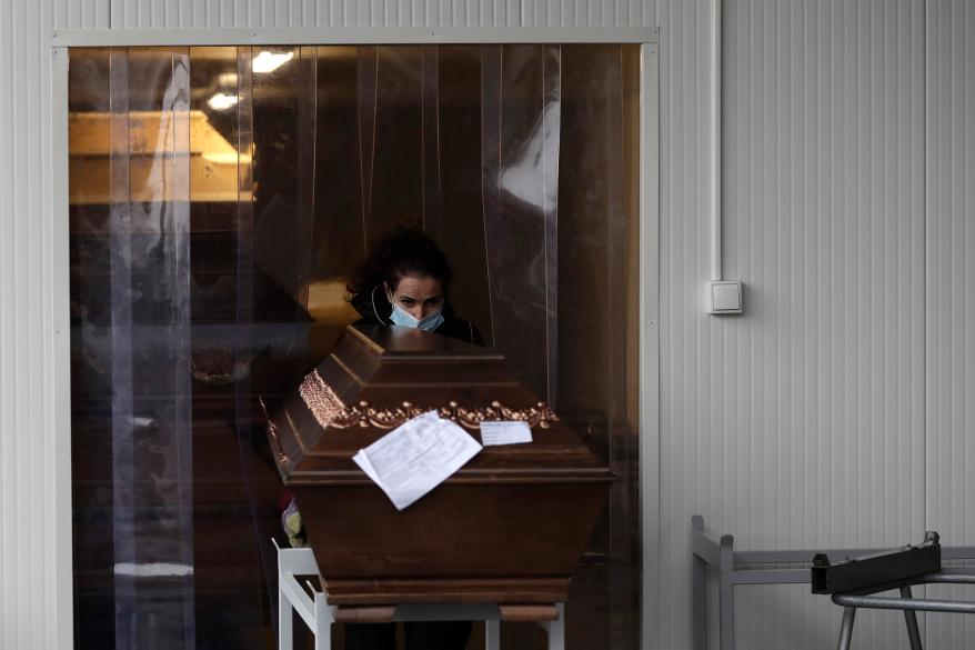 A worker moves a casket into an overflow cold storage container placed outside a crematorium in Ostrava, Czech Republic, Thursday, Jan. 7, 2021.