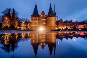 The medieval Holstentor is reflected in water in Luebeck, Germany, Monday, Jan. 4, 2021.