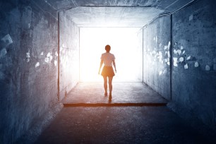 Woman walking through a dark tunnel.