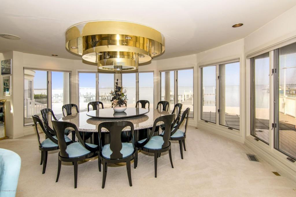 A connected dining room alcove has a large, three-tiered gold lighting fixture with views of the bay. 