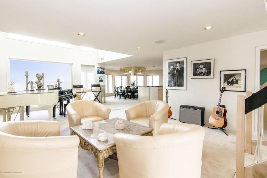 The living room has two guitars, a piano, two director's chairs and old movie posters.