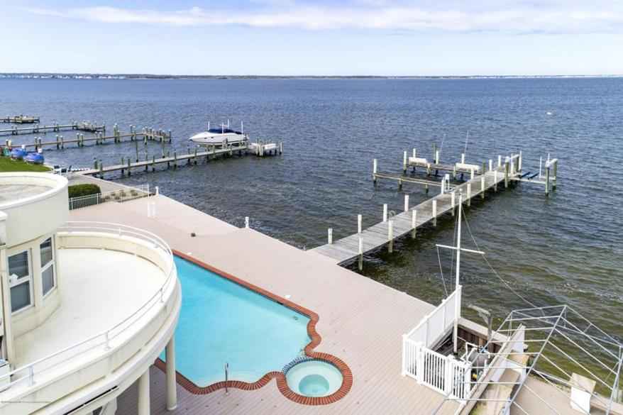 An outdoor patio surrounds a heated pool and spa, from which a not-too-long dock extends directly into the bay.