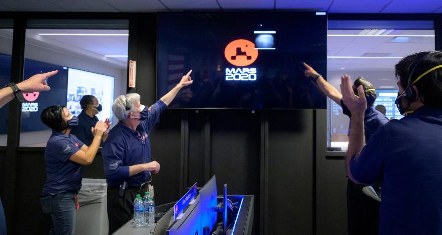 members of NASA's Perseverance rover team react as the first images arrive moments after the spacecraft successfully touched down on Mars, February 18, 2021.