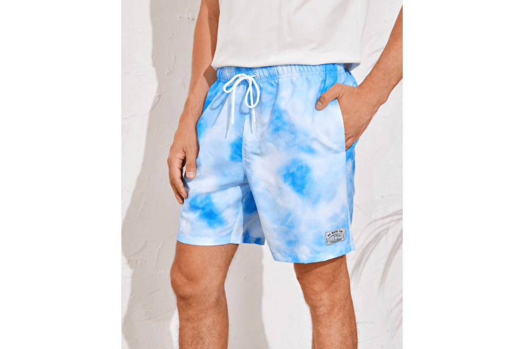 A man in a white shirt and blue tie-dye swim trunks 