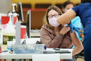 A health care worker gives a coronavirus vaccine to a patient at a COVID-19 vaccination site at the Aqueduct Race Track in Queens.