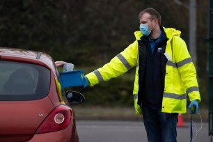 A coronavirus test is handed through a car window to a member of staff at a temporary coronavirus testing centre at Stoke Gifford Park