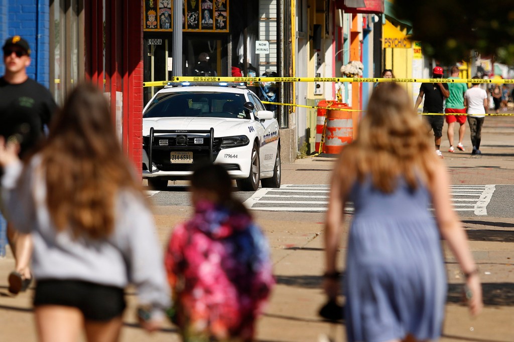 Tourists navigate police tape blocking several streets along the Virginia Beach Oceanfront.