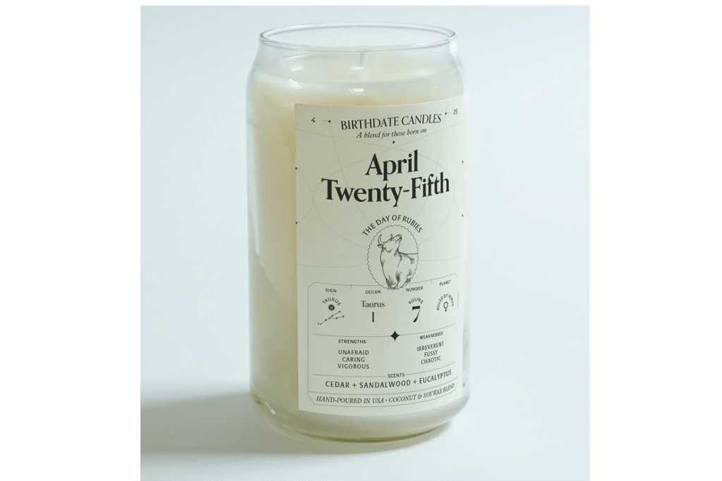 A tall white candle with April 25 on it and the zodiac sign 
