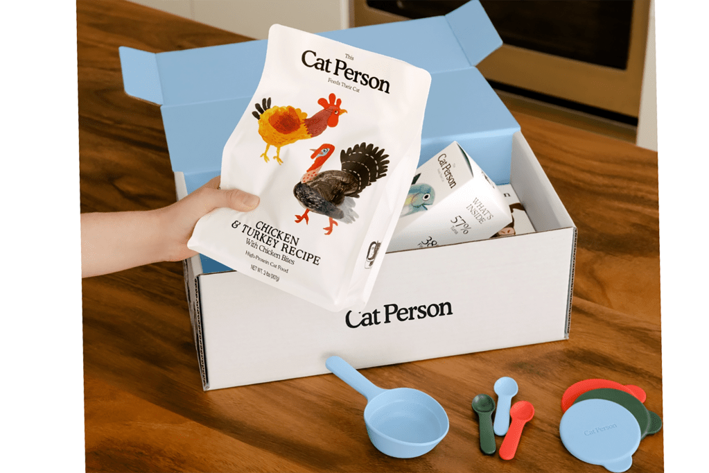 A box of Cat Person brand food and measuring cups 