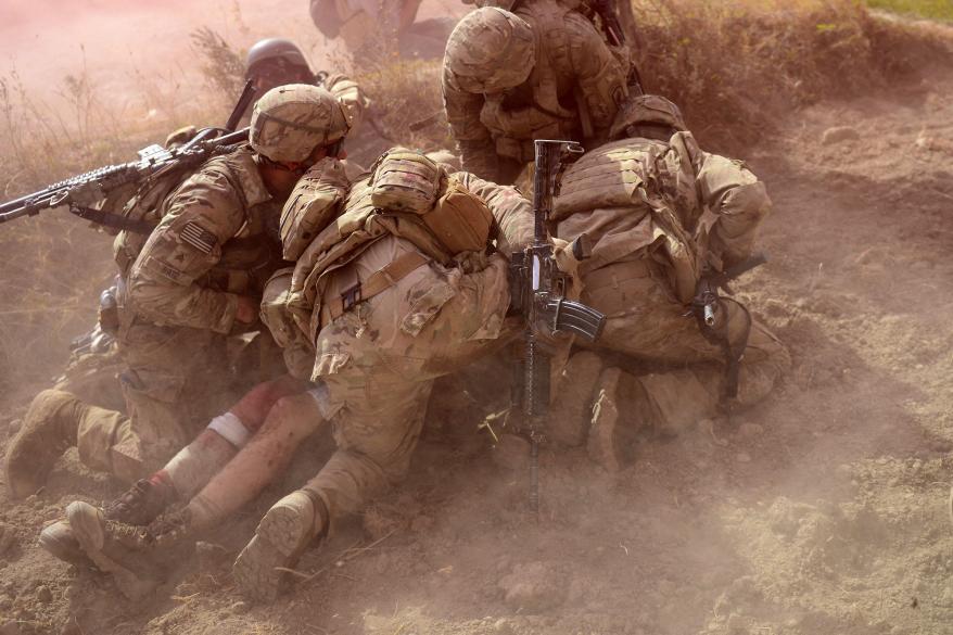 US Army soldiers protect a wounded comrade from dust and smoke flares after an Improvised Explosive Device (IED) blast during a patrol near Baraki Barak base in Logar Province in Afghanistan on October 13, 2012.