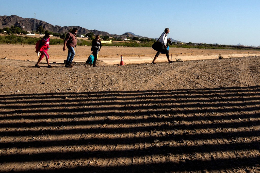 Migrants from Colombia cross the United States and Mexico border to turn themselves over to authorities on May 13, 2021 in Yuma, Arizona.