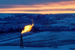 A natural gas flare on an oil well pad burns as the sun sets outside Watford City, North Dakota January 21, 2016.