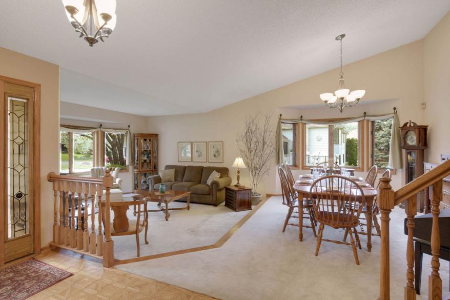 Upon entering, guests see a white carpeted dining room and, down a step, a living room with a large bay window.
