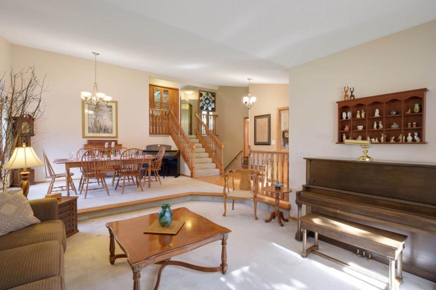 The white carpeting in the recessed living room continues up a step into the dining room.