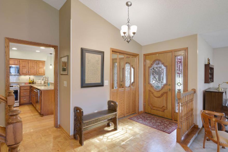 The five-bedroom, two-and-a-half bathroom home has a stone walkway leading to a wood door with leaded glass windows and a sidelight window to the left of the door.