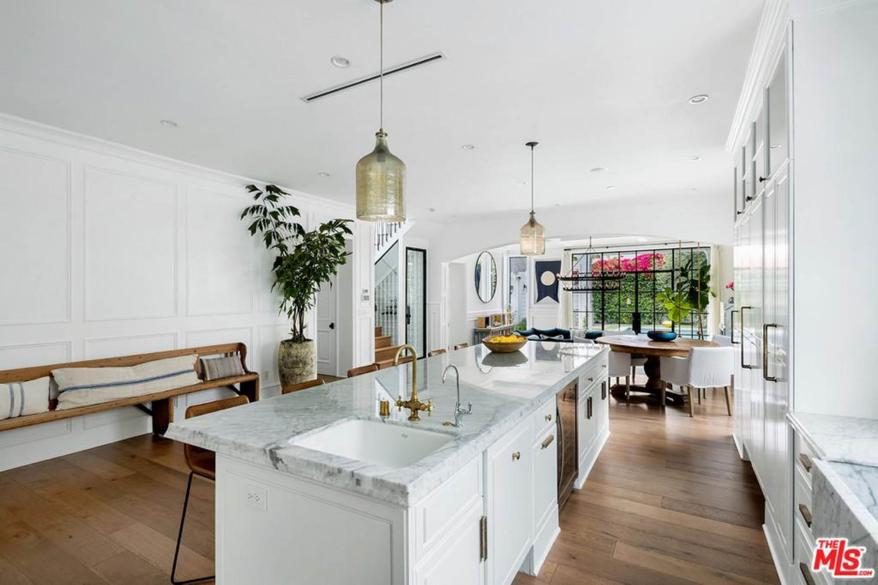 Arranged around a huge island with a Carrara marble sink and a six-seat snack counter, the high-end gourmet kitchen steps down to a family room.