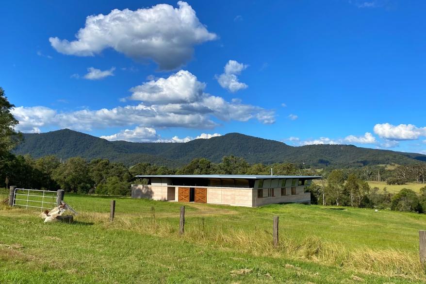 The house is designed with horizontal lines designed to blend in with the environment. Towering mountains provide a backdrop behind the house.