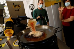 Chef Maria Munoz watches as a robot created by Spanish companies BR5 and Mimcook makes paella during a demonstration at a warehouse in San Fernando de Henares, outside Madrid, Spain, May 20, 2021.