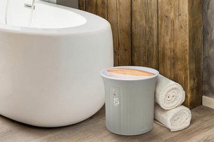 A small towel warming bucket sits on the floor of a bathroom