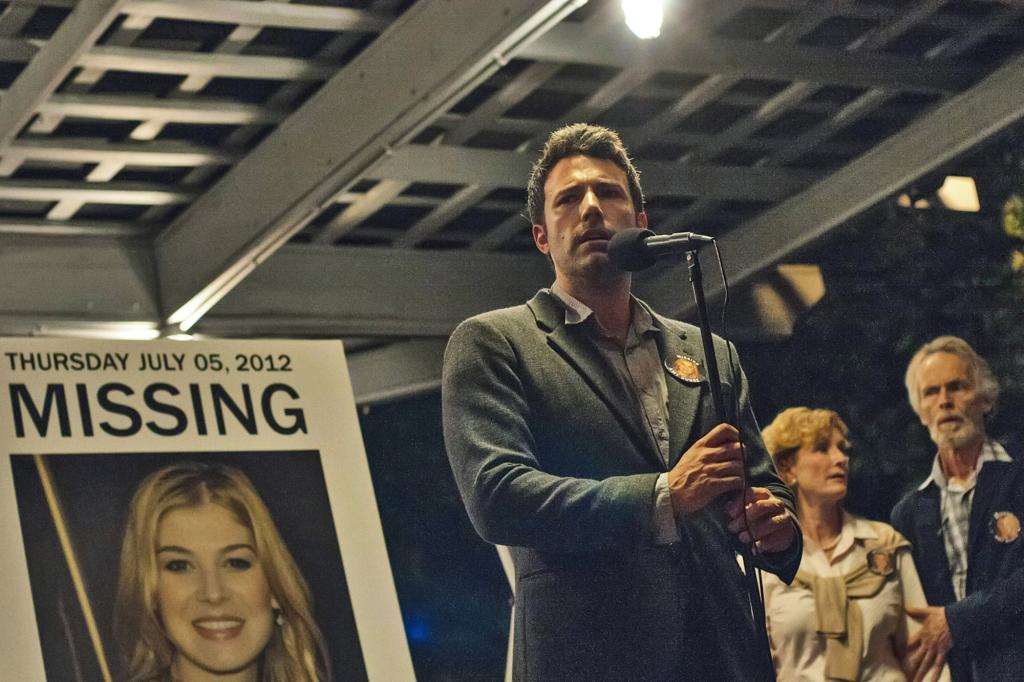 GONE GIRL, from left: Rosamund Pike (in poster), Ben Affleck, Lisa Banes, David Clennon, 2014. ph: Merrick Morton/TM and ©Twentieth Century Fox Film Corporation. All rights reserved./Courtesy Everett Collection