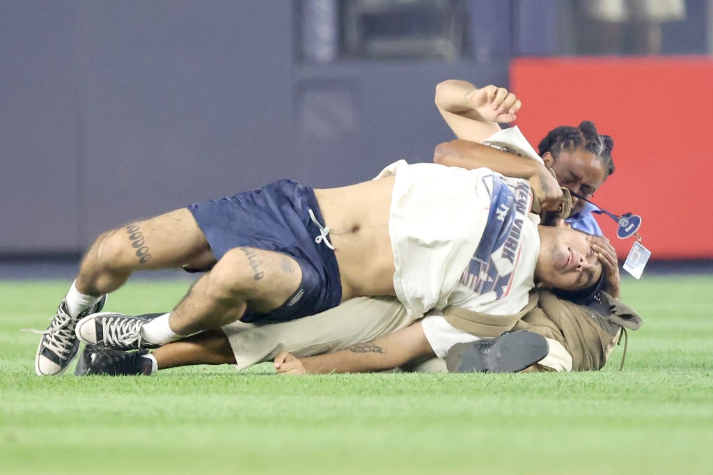 Yankees fan Leo Lertora gets manhandled by security after trespassing the field.
