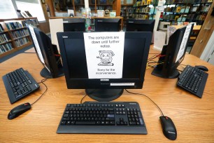 In this Aug. 22, 2019, file photo, signs on a bank of computers tell visitors that the machines are not working at the public library in Wilmer, Texas.