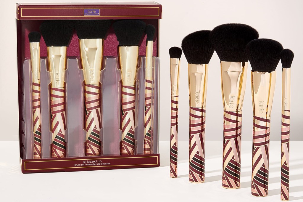 Five gold and black makeup brushes inside product box and standing upright 