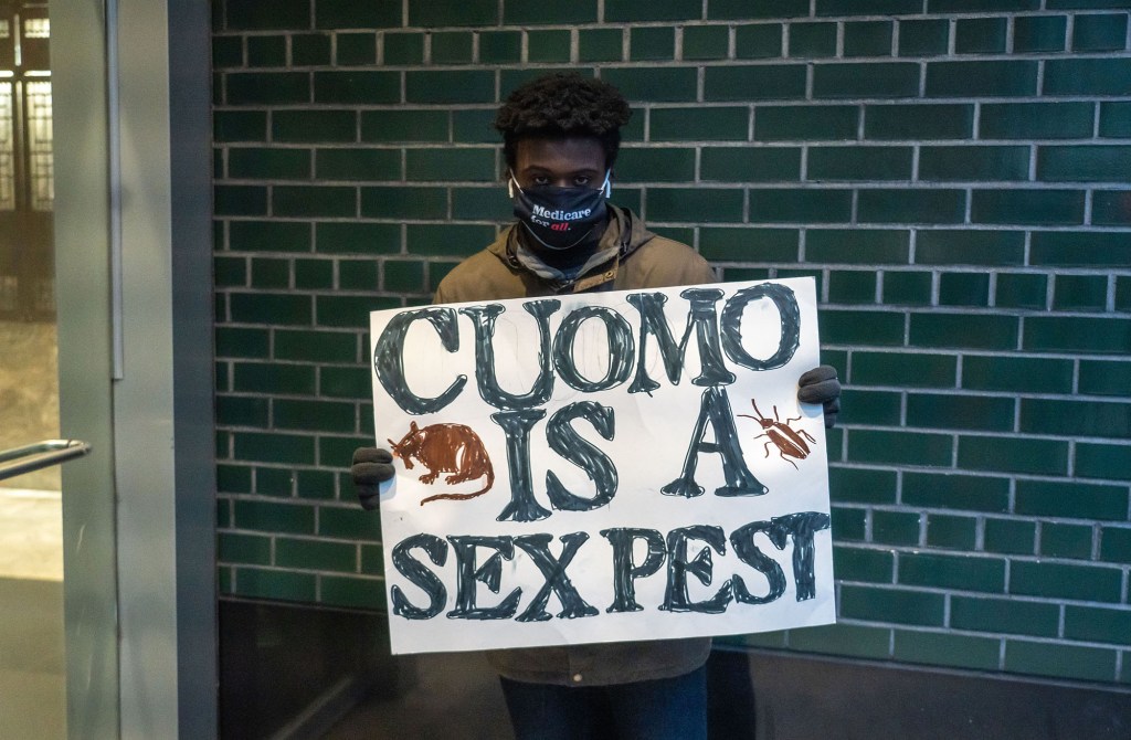 A protester holds a placard that says Cuomo is a sex pest.