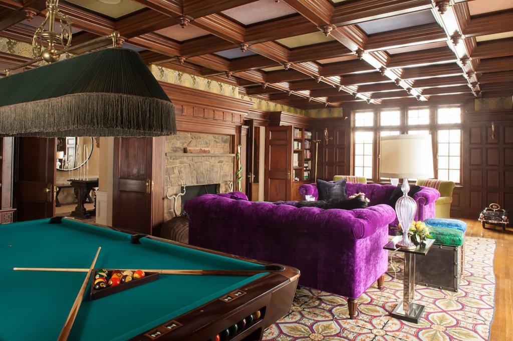 The billiards room has coffered ceilings and purple velvet couches.