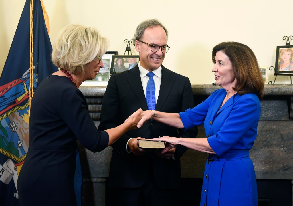 Kathy Hochul is sworn in as governor of New York by New York Chief Judge Janet DiFiore while her husband William Hochul holds a bible.