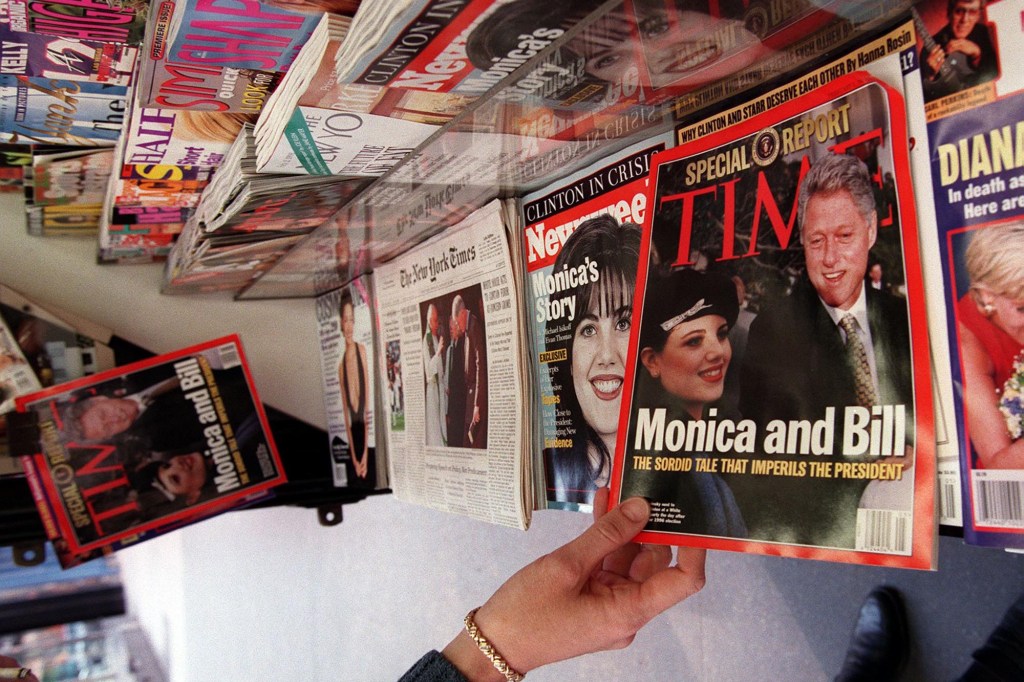 A woman reaches for a newsstand copy of Time Magazine featuring President Bill Clinton and former White House intern Monica Lewinsky.