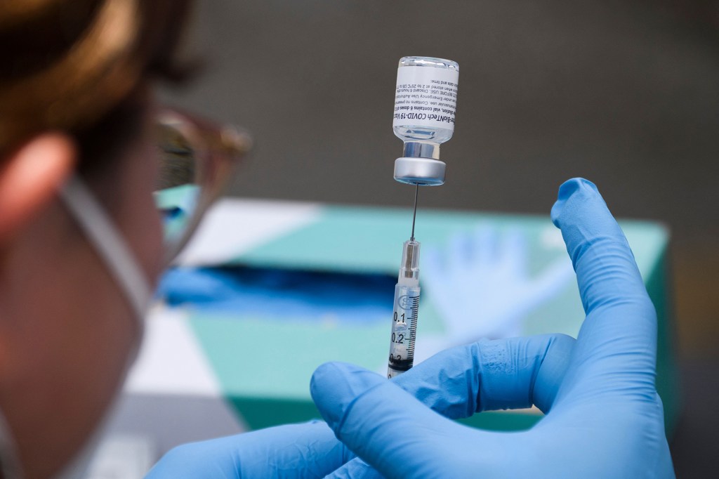 A syringe is filled with a first dose of the Pfizer COVID-19 vaccine.