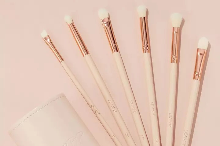 Five pink makeup brushes next to brush holder