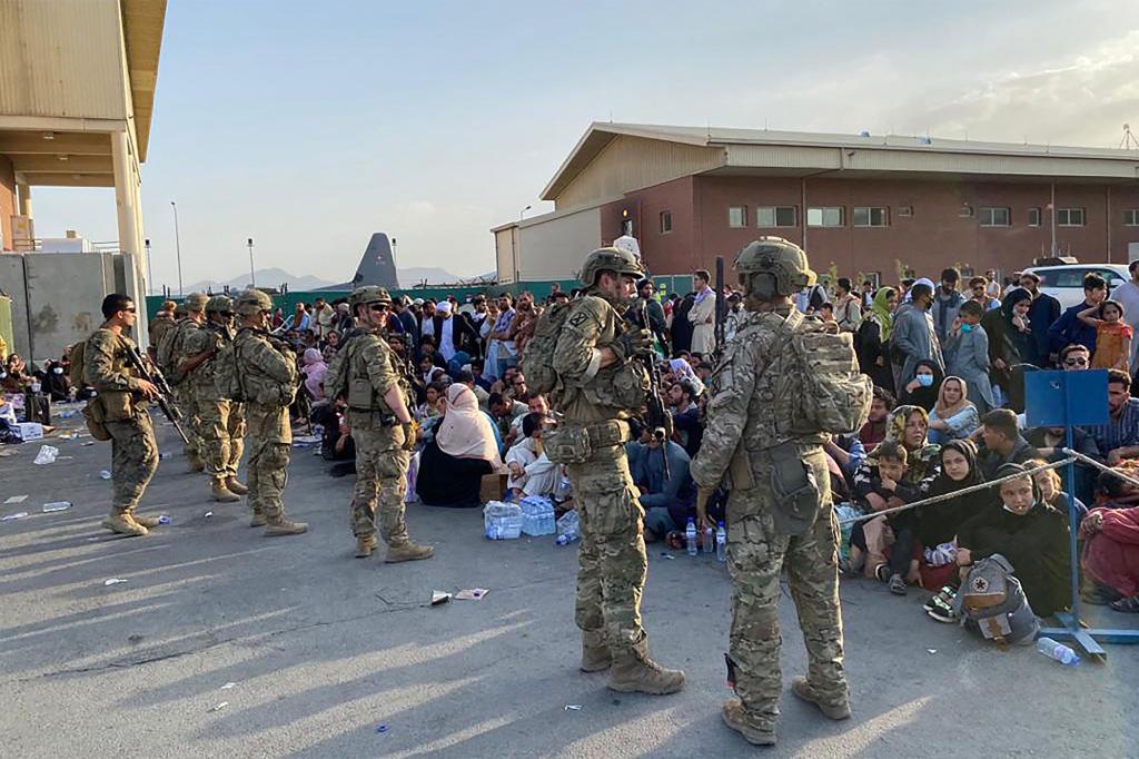 US soldiers stand guard as Afghan people wait to board a US military aircraft to leave Afghanistan