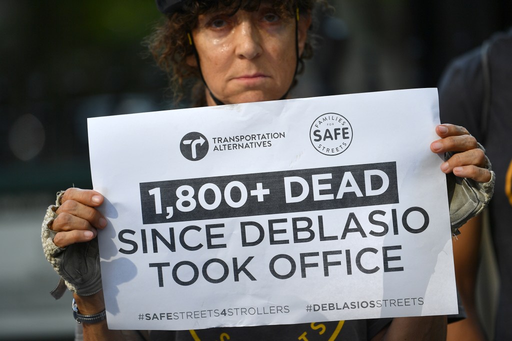 A protester part of Transportation Alternatives holds a sign calling out the amount of traffic deaths during the de BLasio administration.